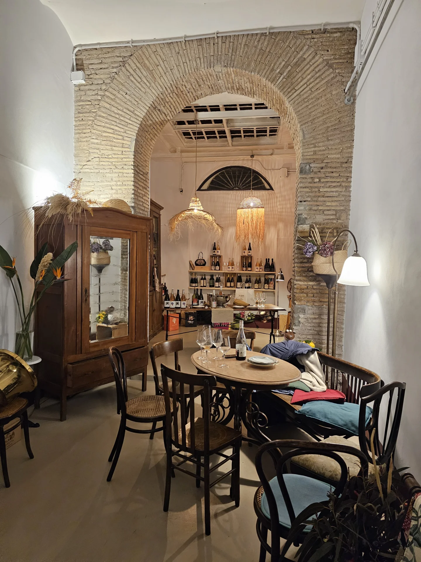 Das Wohnzimmer von [[nt]]Accanto [[/nt]] – reservierter Raum des Caffè Novecento mit Backsteinbogen, rundem Tisch und Auswahl an Naturweinen, Rom